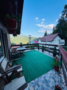 a patio with a green yard with chairs and a house at Vila Gabi in Buşteni