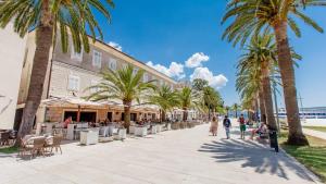 a group of people walking down a sidewalk with palm trees at Riva Guesthouse in Tivat