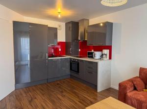 Una cocina con electrodomésticos de acero inoxidable y gabinetes rojos. en House Novo Appt 10min de Paris Centre, en Aulnay-sous-Bois