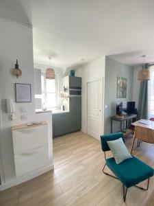 a living room with a blue chair and a kitchen at La tranquillité trouvillaise in Trouville-sur-Mer