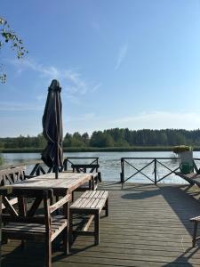 a wooden table with an umbrella and benches on a dock at Tunnelmallinen maalaistaloelämys in Vehmaa