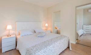 ein weißes Schlafzimmer mit einem weißen Bett und zwei Lampen in der Unterkunft Villa Diana in Podstrana + 36 Fotos