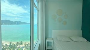una camera da letto con finestra affacciata sull'oceano di Ubuntu Mường Thanh Nha Trang Apartment a Nha Trang