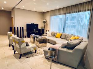 a living room with a couch and chairs and a tv at Villa Bahia Golf beach - Bouznika in Casablanca