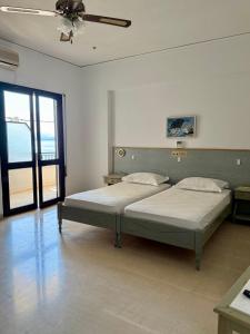 a bedroom with two beds and a ceiling fan at Hotel Derveni Georgiadis in Stómion