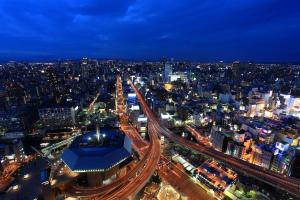 eine nächtliche Aussicht auf eine Stadt mit Autobahn in der Unterkunft Hotel Monterey Grasmere Osaka in Osaka