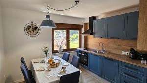 a kitchen with a table and blue cabinets at Sunčev breg in Tuheljske Toplice