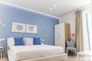 1 dormitorio con paredes azules, 1 cama y 1 silla en Le Chicche by MONHOLIDAY, en Monopoli