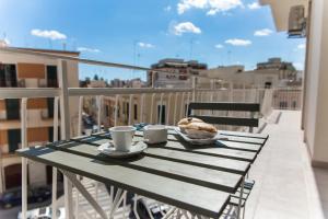 Una mesa con un sándwich y tazas de café en un balcón. en Le Chicche by MONHOLIDAY, en Monopoli