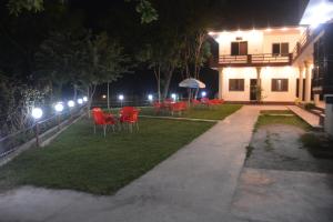 a yard with red chairs and a building at night at Budget Rooms with Garden by Galiyat Inn Balakot in Bālākot