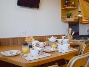 a wooden table with cups and saucers on it at Craigrossie Cottage in Auchterarder