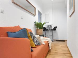 a orange couch with pillows on it in a living room at Zentrale Wohnung für 9 Gäste nahe Schlossplatz in Stuttgart +24 photos