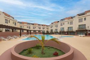 a pool with a palm tree in the middle of a courtyard at Lightbooking Costa Antigua Fuerteventura in Costa de Antigua