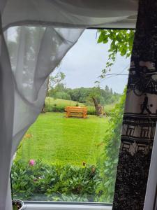 a window view of a garden with a wooden bench at Marija in Krāslava