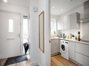 eine weiße Küche mit Waschmaschine und Trockner in der Unterkunft Wagtails in Dartmouth