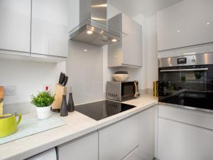 eine Küche mit weißen Schränken und einer Mikrowelle in der Unterkunft Wagtails in Dartmouth + 12 Fotos