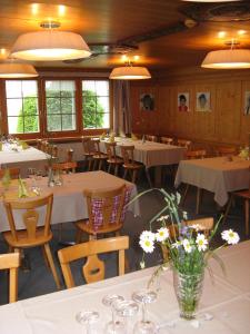 un restaurant avec des tables blanches, des chaises et des fleurs dans l'établissement Waldgasthaus Lehmen, à Weissbad