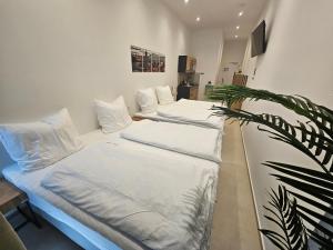 two beds with white sheets in a room with a plant at ApartHotel Rahl in Hamburg +10 photos