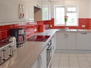 a kitchen with white cabinets and red tiles at Rudda Farm House - Uk2491 in Staintondale