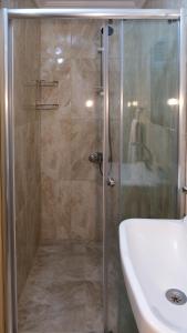 een douche met een glazen deur naast een wastafel bij Sarp Bungalov in Kemalpasa