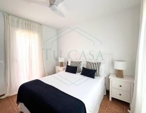 a bedroom with a white bed with black and white pillows at Ático Jardín del Golf, Casa Alma in Chiclana de la Frontera