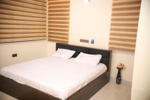 a bed with white sheets and pillows in a room at Stylish Affordable Studio Apartment RealShala Homes- Accra in Ashalebotwe