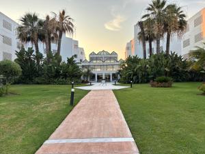 a pathway in a park with palm trees and a building at Playa Rocio calm beachfront apartment- 2bdr in Marbella