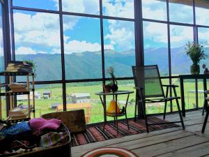 a room with a large window with a view of mountains at Nadiani Hostel in Omalo