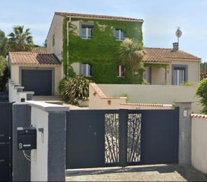 a house with a blue gate and a building at Agréable maison avec jacuzzi in Vinassan