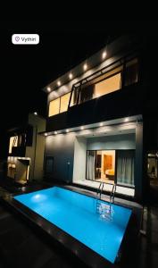 a swimming pool in front of a house at night at LA VILLA Resort in Vythiri