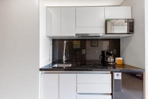 a white kitchen with a sink and a microwave at Fabulous Loft With Pool in Cancún