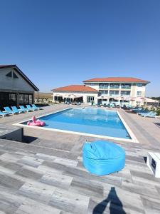 a swimming pool with chairs and a large building at Pensiunea Aura Deltei in Murighiol