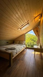 Bett in einem Holzzimmer mit einem großen Fenster in der Unterkunft Amonte Mountain Resort in Muntele Rece