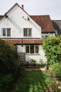 ein weißes Haus mit 2 Stühlen und einer Terrasse in der Unterkunft Straw Plaiters Cottage in Wendover