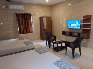 a room with a bed and chairs and a television at Limra Farm House in Pollāchi