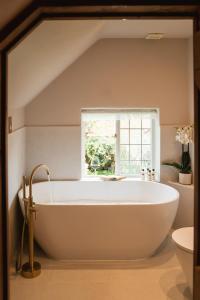 eine große weiße Badewanne im Bad mit Fenster in der Unterkunft Straw Plaiters Cottage in Wendover + 28 Fotos