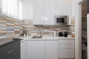 a white kitchen with a sink and a microwave at Università & Strada Nuova - Lovely Suite Scaldasole in Pavia