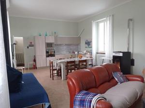 a living room with a leather couch and a kitchen at Rifugio escursionistico ex-scuola Grassi, Bubbio in Bubbio