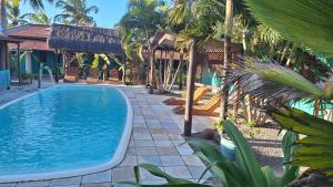 une piscine dans un complexe hôtelier avec des palmiers dans l'établissement Hawaii Flats, à São Miguel do Gostoso