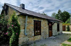 a small stone building with a door and flowers at Suure-Jürna Puhkepesa in Kahutsi