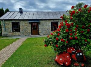 a stone house with red roses in front of it at Suure-Jürna Puhkepesa in Kahutsi +7 photos