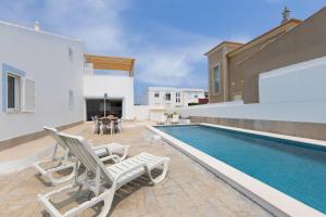 a villa with a swimming pool and two lawn chairs at Sunny Sagres in Sagres