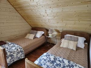 two beds in a room with wooden walls at Leonówka in Jegliniec