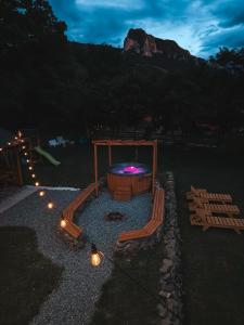 a backyard with a fire pit with benches and lights at Cabana Mirajul in Rimetea