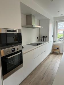 a kitchen with white cabinets and a stove top oven at Maison Lymoen, gezellige gloednieuwe woning aan zee in De Panne +52 photos