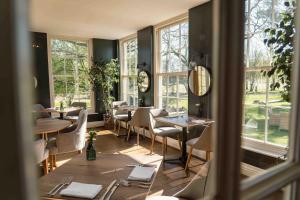 a restaurant with tables and chairs and windows at Yorebridge House in Bainbridge