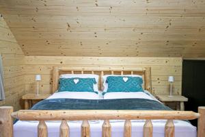 a wooden bedroom with a bed with blue pillows at Chalet pod Strážovom in Zliechov