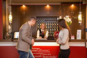 a man and two women standing in front of a counter at Montana-Hotel Ellwangen in Ellwangen