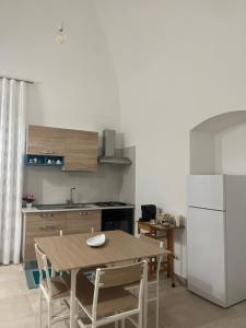 a kitchen with a wooden table and a white refrigerator at De Medici Home in Terlizzi