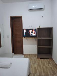 a room with a tv on a shelf and a bed at Pousada Manu Guajiru in Trairi